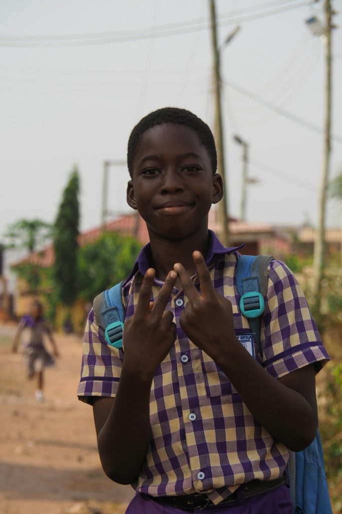 Smiling young Black boy in a school uniform with a backpack